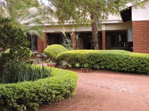 a building with bushes and a bench in front of it at Perigrin Rest House in Karatu