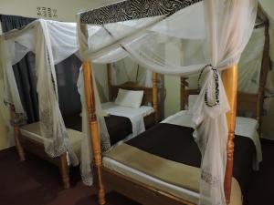 a bedroom with two bunk beds with white drapes at Perigrin Rest House in Karatu