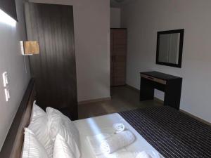 1 dormitorio con cama con almohadas blancas y escritorio en Rodolithos Beach Studios en Stavros