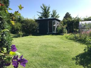 einen Garten mit einem kleinen Haus im Hintergrund in der Unterkunft Cutest annex - close to Heatherhill and sea :-) in Vejby