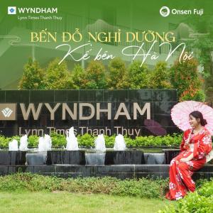 une femme assise sur l'herbe tenant un parapluie dans l'établissement Room in Wyndham Thanh Thuy Hot Spring MyHome, à La Phu