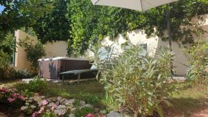 um jardim com um banco debaixo de um guarda-chuva em Accanto Alle Mura Rooms & Relax Spa em Sirolo