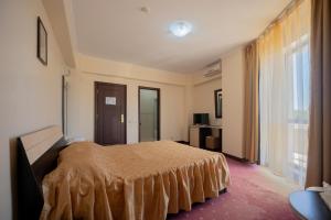 sypialnia z łóżkiem i dużym oknem w obiekcie Hotel Coral w mieście Eforie Nord