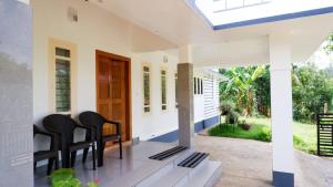 a porch of a house with black chairs at WAYANAD OASIS VILLa in Kalpetta