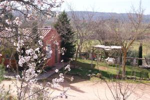 a red barn in a garden with pink flowers at Casas Rurales Los Cortijos in Alcaraz