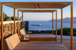 a bedroom with two beds and a cruise ship in the ocean at Strogili in Oia