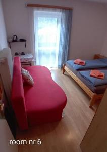 a room with a red couch and a bed and a window at Sportpension Schober in Obertraun
