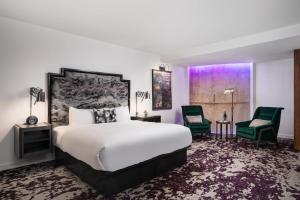 a bedroom with a large bed and two green chairs at JW Marriott Savannah Plant Riverside District in Savannah