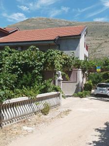 a house with a fence and a car parked in front of it at GM - Studio Apartment in Trebinje
