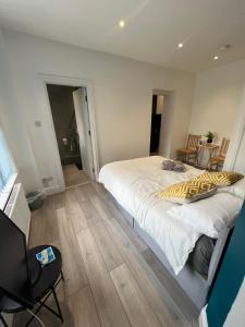 a bedroom with a large white bed and wooden floors at Barnet Studios in New Southgate