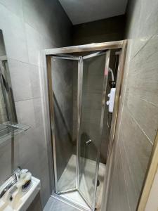 a shower with a glass door next to a sink at Barnet Studios in New Southgate