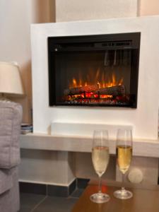 two glasses of wine on a table in front of a fireplace at Lipno Holiday Penthouse in Lipno nad Vltavou