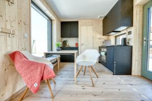 a kitchen with wooden walls and counters and white chairs at Tiny Design-Modulhaus mit 33 m² in Grimma