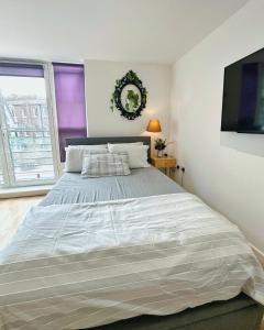 a bedroom with a large bed and a flat screen tv at Twickenham studio private apartment in Twickenham