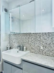 y baño blanco con lavabo y ducha. en Twickenham studio private apartment en Twickenham