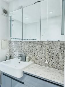 Baño blanco con lavabo y espejo en Twickenham studio private apartment en Twickenham