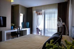 a bedroom with a bed with a desk and a window at Pelagos Suites Hotel & Spa in Kos
