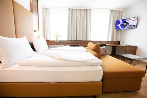 um quarto de hotel com uma cama grande com almofadas brancas em Das Reinisch Hotel & Restaurant em Schwechat