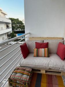 um sofá sentado numa varanda com almofadas vermelhas em Cozy Apartment em Santa Luzia