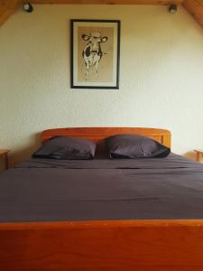 a bed with a picture of a cow on the wall at Appartement Les rousses, Jura in Les Rousses