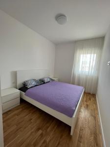 a bedroom with a purple bed and a window at Apartman Čapljina in Čapljina