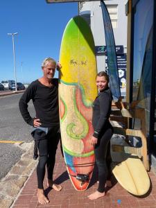 a man and a woman standing next to surfboards at Cape Capsules in Muizenberg