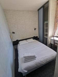 een slaapkamer met een wit bed en handdoeken bij hotel le tourisme in Embrun