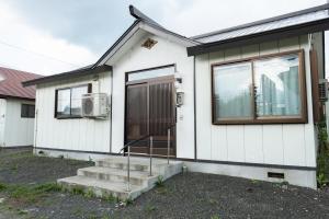 uma casa branca com uma porta e janelas em Furano - House / Vacation STAY 56483 em Furano