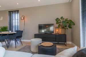 a living room with a tv and a table at Luxe appartement dichtbij strand en zee, in het hart van de bollenstreek in Noordwijkerhout