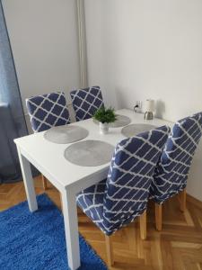 Biały stół i krzesła z niebieskim dywanem w obiekcie Płyta 129 w mieście Gdynia