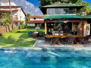 una casa con tavolo e sedie accanto a una piscina di JaParaíso Pousada Ateliê a Japaratinga