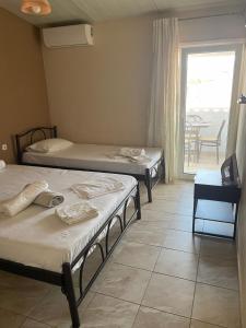 a room with three beds and a window with a table at House Filippos in Sarti