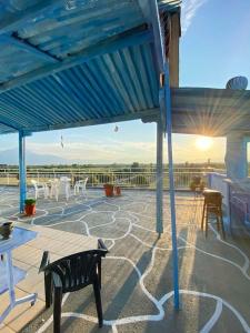 a patio with a blue roof with tables and chairs at Blue Sky Apartment Paralia in Paralia Katerinis