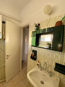 a bathroom with a sink and a window and a door at Blue Sky Apartment Paralia in Paralia Katerinis