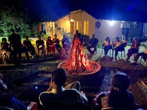 a group of people sitting around a fire at night at Abad Brookside Wayanad in Vythiri