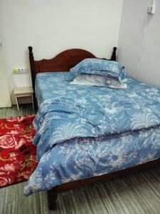 1 cama con edredón azul y almohadas en Homestay D'Murni, en Kampung Gurun