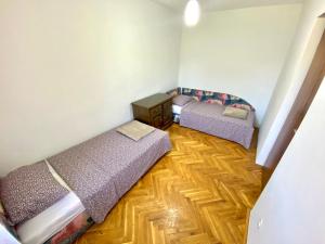 two beds in a room with a wooden floor at Apartman Akvamarin in Vrnjci
