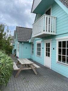 una casa azul con una mesa de picnic delante de ella en Vrijstaande luxe Finse blokhut 2-6 of 2-8 pers, en Kropswolde