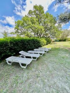 a row of white lounge chairs on the grass at Maison de Bernard in Le Beausset
