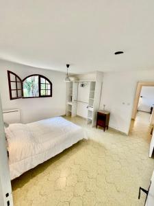 a white bedroom with a bed and a window at Maison de Bernard in Le Beausset