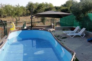 einen Pool mit Sonnenschirm und Stuhl in der Unterkunft Kuća za odmor Ante in Lišane Ostrovičke