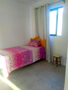 una camera da letto con un letto con una coperta rosa e una finestra di Residence Lavande a Beau Bassin-Rose Hill