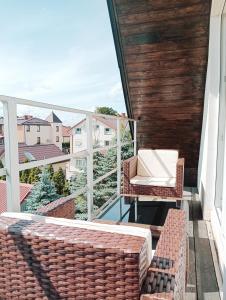 a balcony with two wicker chairs and a table at BaltiQ Łeba in Łeba