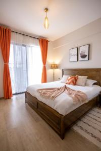 a bedroom with a large bed with orange curtains at LeR Homes in Nairobi