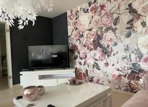 uma sala de estar com televisão e papel de parede florido em Résidence Birdie em Jalhay