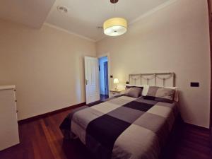 1 dormitorio con 1 cama con manta blanca y negra en MONFORTE CENTRO APARTAMENTO, en Monforte de Lemos