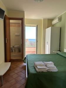 ein Schlafzimmer mit einem grünen Bett und Handtüchern darauf in der Unterkunft Ravè in Praia a Mare