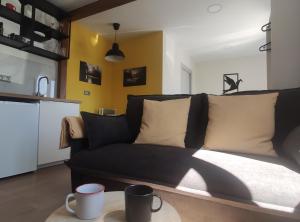 a living room with a black couch and a kitchen at A Casiña do Camiño in Baamonde