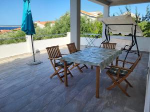 a table and chairs on a porch with an umbrella at Apartment Gligora in Mandre