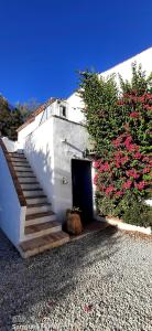 a white building with a door and stairs with flowers at Attico Los Montes with private pool in Viñuela